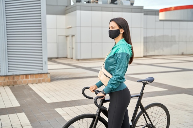 Sportliche Dame, die den Lenker des Fahrrads hält und vor sich hinschaut