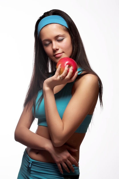 Sportliche Frau beißt einen roten Apfel