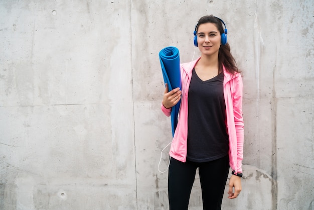 Sportliche Frau, die eine Trainingsmatte hält.