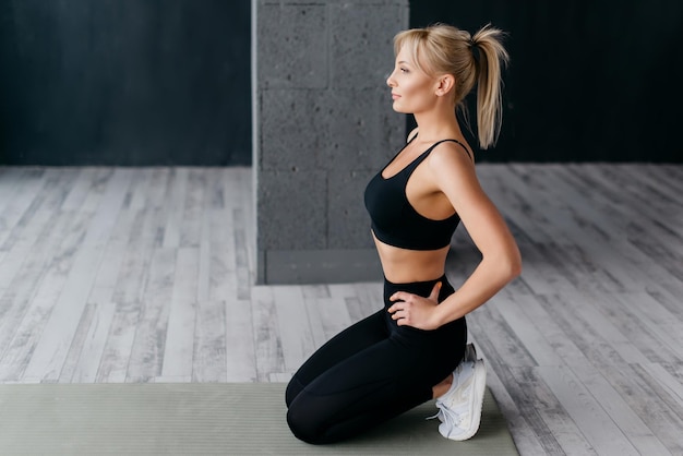 Foto sportliche frau, die im fitnessstudio auf der matte sitzt