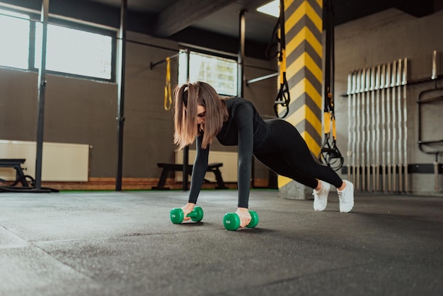 Sportliche Frau, die im Fitnessstudio Übungen mit Hanteln macht