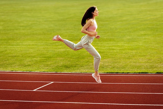 Sportliche Frau, die im Stadion trainiert Smilie attraktives Mädchen, das Übung macht