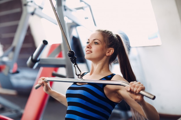 Sportliche Frau, die Maschine zum Zurückpumpen von Muskeln verwendet