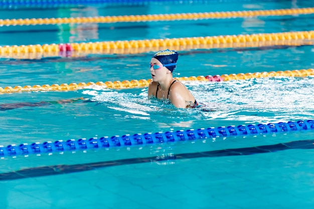 Sportliche Frau, die mit Schwimmhut und Brille im Schwimmbad schwimmt