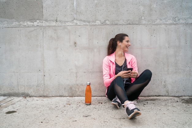 Sportliche Frau, die sein Telefon benutzt