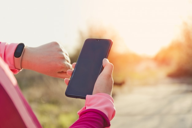 Sportliche Frau mit Fitness-Tracker und Smartphone