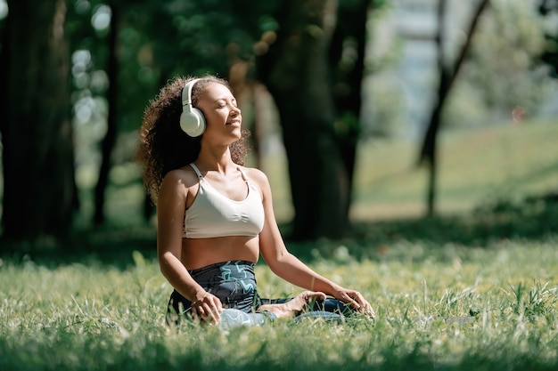 Sportliche Frau mit Kopfhörern, die sich beim Sitzen zur Musik entspannt