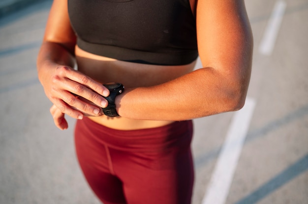 Sportliche Frau mit Smartwatch an der Straße