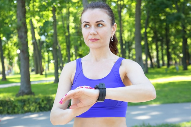 Sportliche Frau schaut auf die Uhr auf seiner Hand