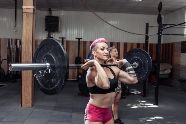 Sportliche Frauen, die Langhantel im modernen Cross-Fitnessstudio halten. Funktionstraining