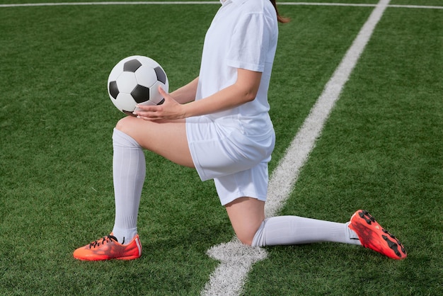 Foto sportliche fußballspielerin mit einem fußball auf dem fußballplatz das konzept des professionellen frauenfußballs