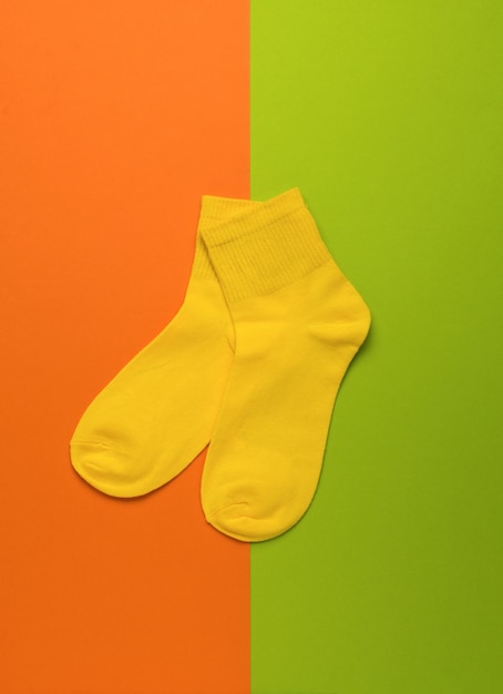 Sportliche gelbe Socken auf grünem und orangefarbenem Hintergrund Flach liegend