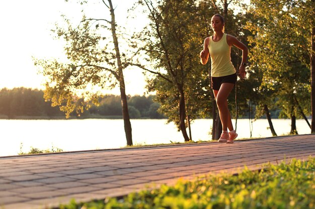 Foto sportliche joggerin, die draußen in der natur läuft und trainiert.