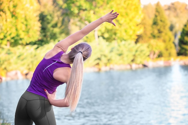 Foto sportliche junge frau, die am flussufer trainiert