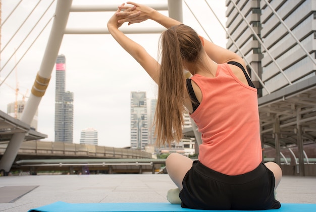Sportliche junge Frau, die Yoga im Freien / aktiven Lebensstil tut