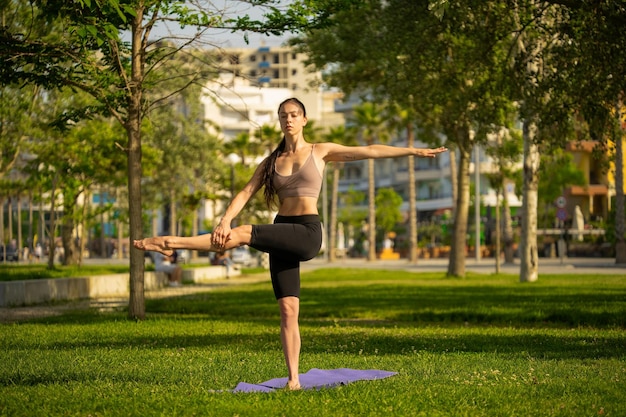 Sportliche junge Frau, die Yoga im Park am Morgen tut