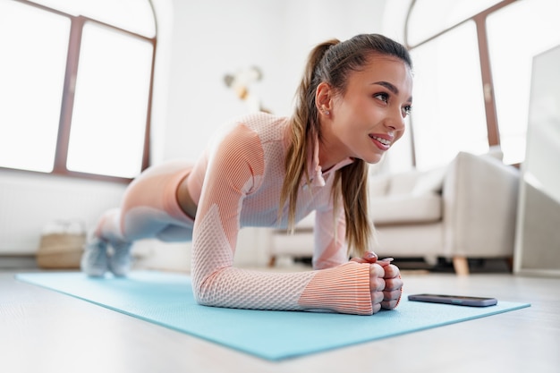 Sportliche junge Frau, die zu Hause Plankenübungen macht