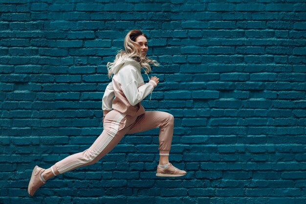 Sportliche junge Frau in einem rosa Sportanzug. Springen und rennen weiblich.