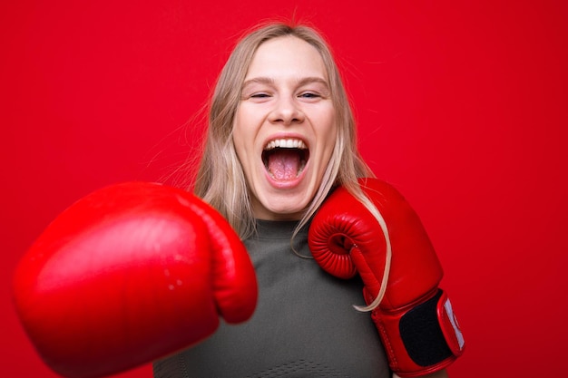 Sportliche junge Frau in roten Boxhandschuhen spielt herum