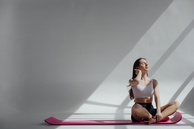 Sportliche junge Frau macht Yoga-Praxis isoliert auf weißem Hintergrund. Konzept des gesunden Lebens
