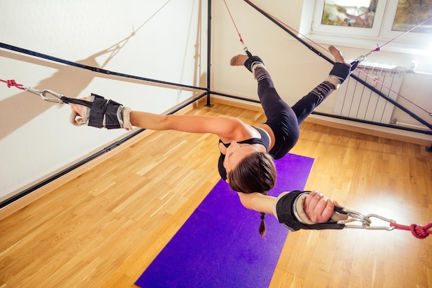 Sportliche junge kaukasische Frau, die Dehnübungen der Ganzkörpermuskulatur macht, trainiert auf aerobem Aero-Streckgurt im Fitnessstudio, Yogi-Matte.