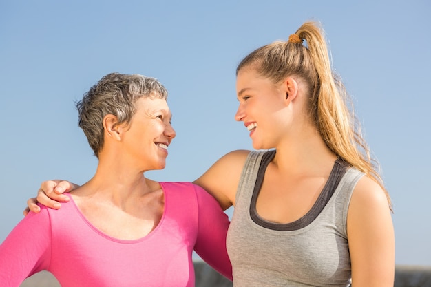 Sportliche Mutter und Tochter, die an einander lächelt