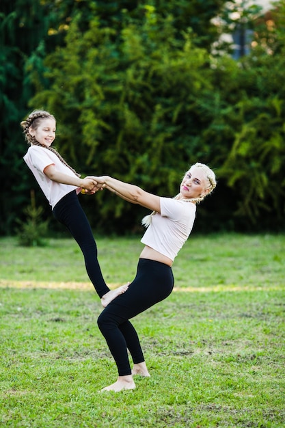 Sportliche Mutter und Tochter. Outdoor-Training auf Gras, Cheerleader-Training