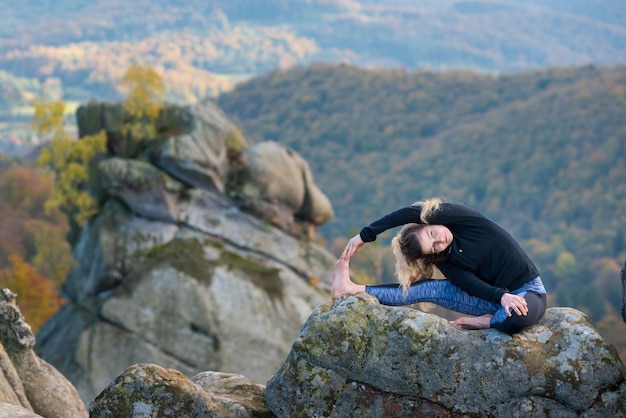 Sportliche sitzfrau übt yoga auf die oberseite des berges