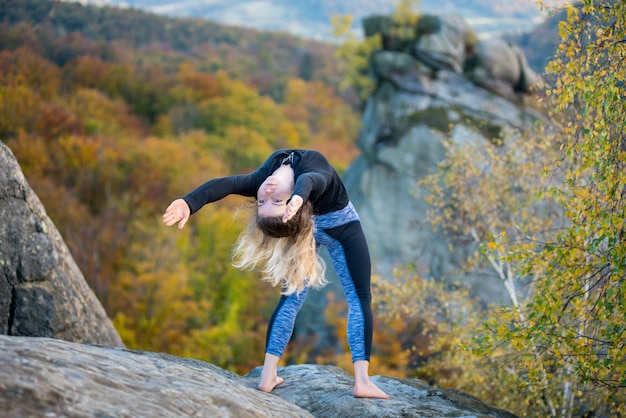 Sportliche Sitzfrau übt Yoga auf die Oberseite des Berges