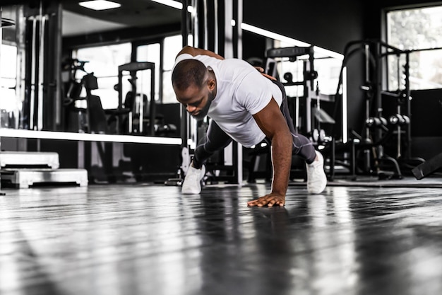 Sportlicher afrikanischer Mann, der Liegestütze in einem Fitnessstudio macht