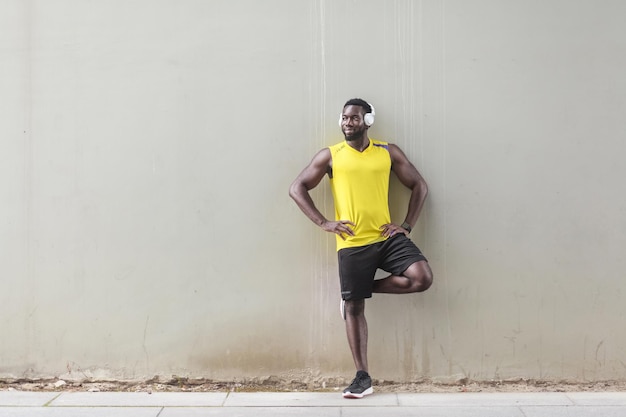 Sportlicher Afro-Mann, der in der Nähe der alten Mauer steht und Morgengymnastik macht