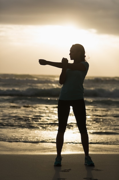 Sportlicher Brunette, der auf den Strand ausdehnt