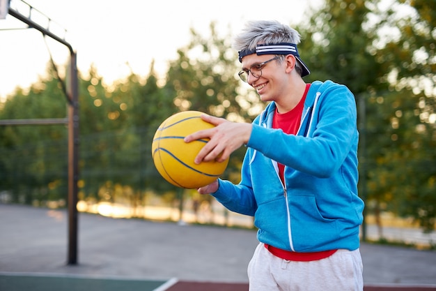 Sportlicher Junge in der Freizeitkleidung scharf auf Basketball