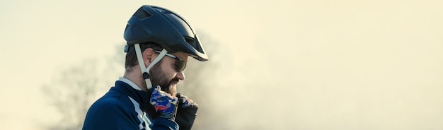 Sportlicher junger Mann mit Brille und Helm schaut in die Ferne. Getöntes Panoramabild.