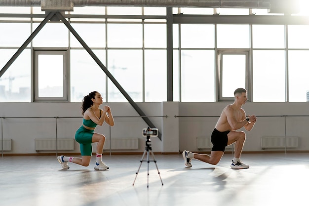 Sportlicher lateinamerikanischer Mann und Frau beim Online-Training im Fitnessstudio mit Übungen Trainingskonzept für Paare