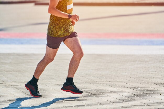 Sportlicher Mann, der in Sportbekleidung auf Stadtstraße joggt