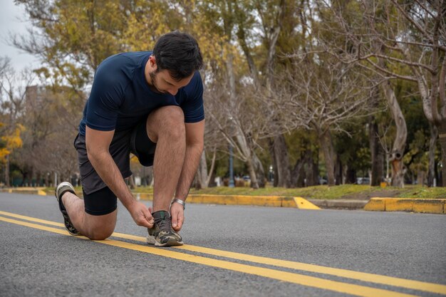 Sportlicher Mann, der seine Schnürsenkel bindet, während er im Freien trainiert