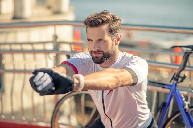 Sportlicher Mann in der Sportbekleidung, die sich auf der Straße ausdehnt