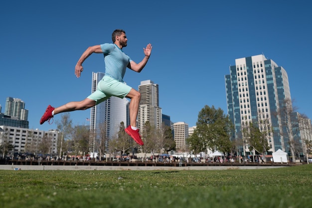 Sportlicher Mann Läufer läuft im Sommer Citi Park junger und aktiver urbaner moderner sexy Jogger