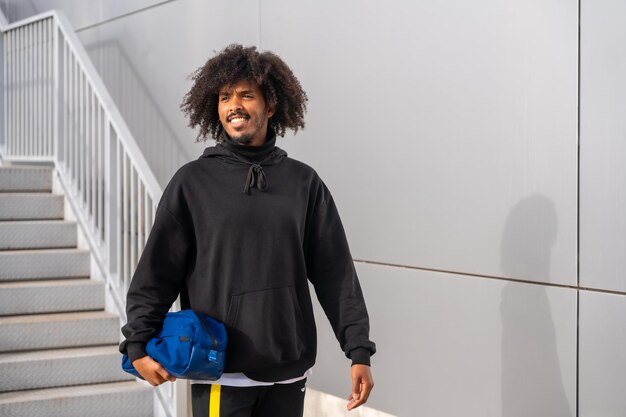 Sportlicher Mann mit Afro-Frisur, der neben der Treppe läuft