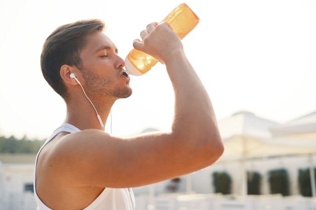 sportlicher Mann mit Kopfhörern Trinkwasser