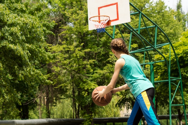 Sportlicher schlanker Teenager, der Basketball spielt