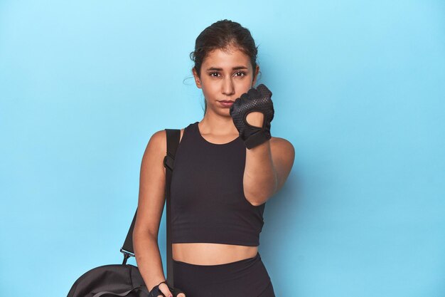 Foto sportlicher teenager mit sporttasche bereit für ein training, der der kamera seine faust zeigt, aggressiver gesichtsausdruck