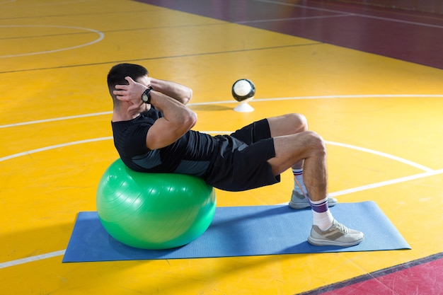 Sportlicher Typ in Sportbekleidung und Fitness-Tracker, der Übungen im Fitnessstudio macht.