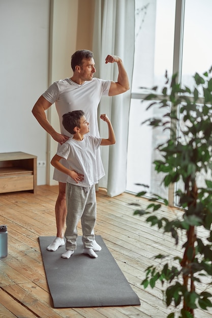 Foto sportlicher vater und sohn zeigen muskeln in der halle