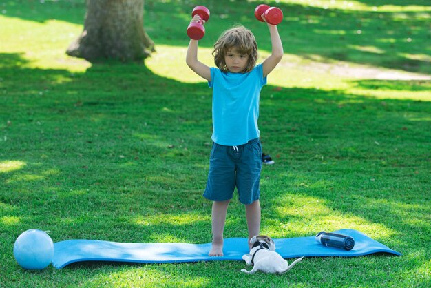 Sportliches Lifestyle-Konzept Sport-Yoga-Kind mit Hantel Junge trainiert im Park