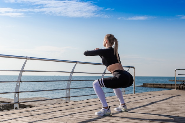 Sportliches Mädchen, das Hocken nahe dem Meer tut