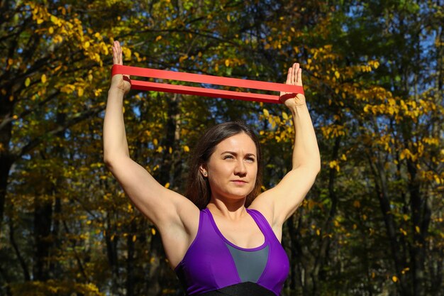 Sportliches Mädchen macht Übungen mit einem Fitness-Gummiband im Park