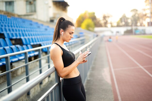 Sportliches Mädchen mit Handy im Stadion Porträt einer sportlichen Frau