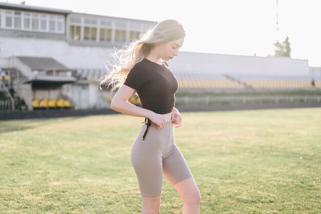 Sportliches Mädchen steht im Stadion Haar entwickelt sich aus dem Wind Foto für Werbung im Sportgeschäft